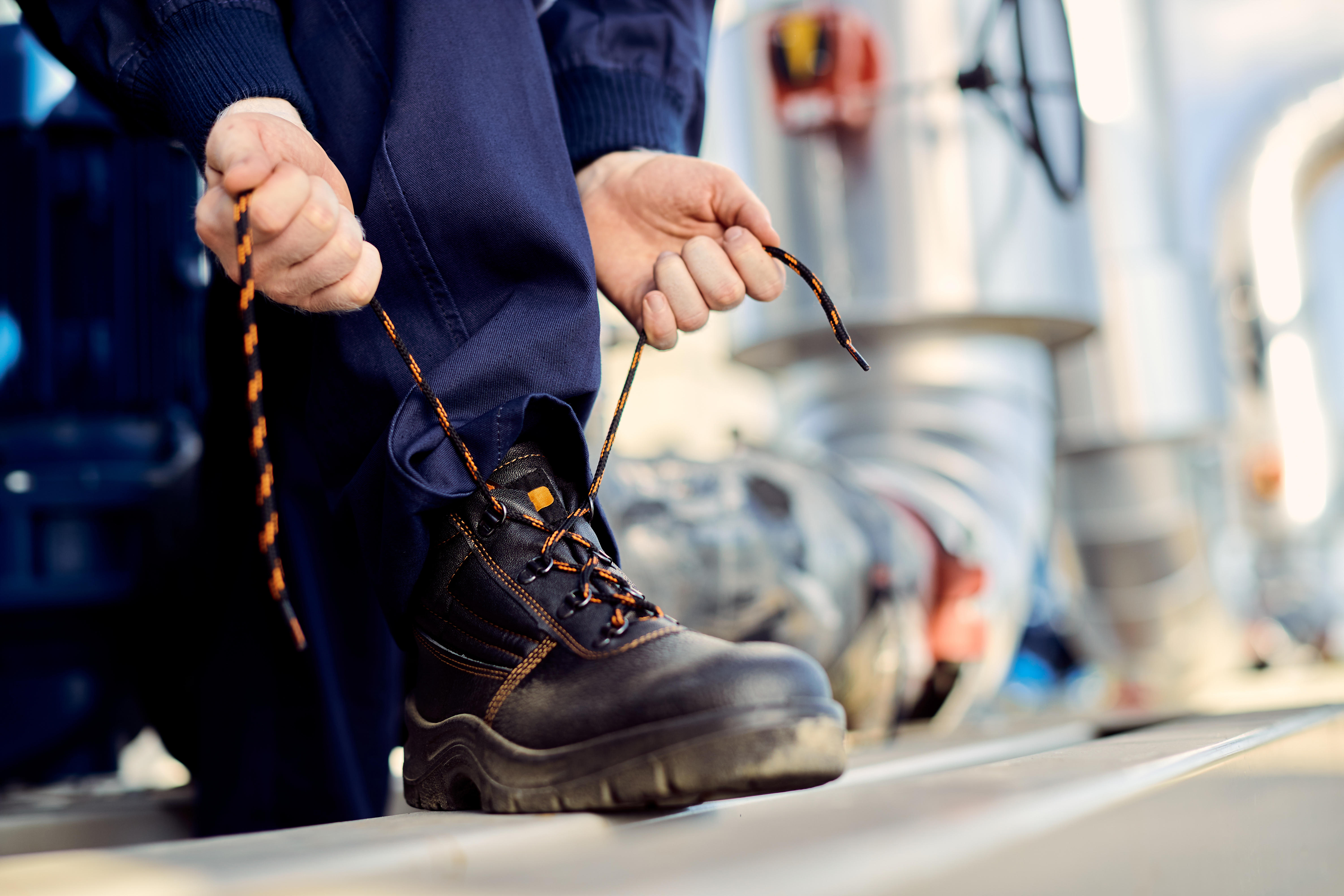 Unrecognizable construction worker tying his shoelace outdoors.